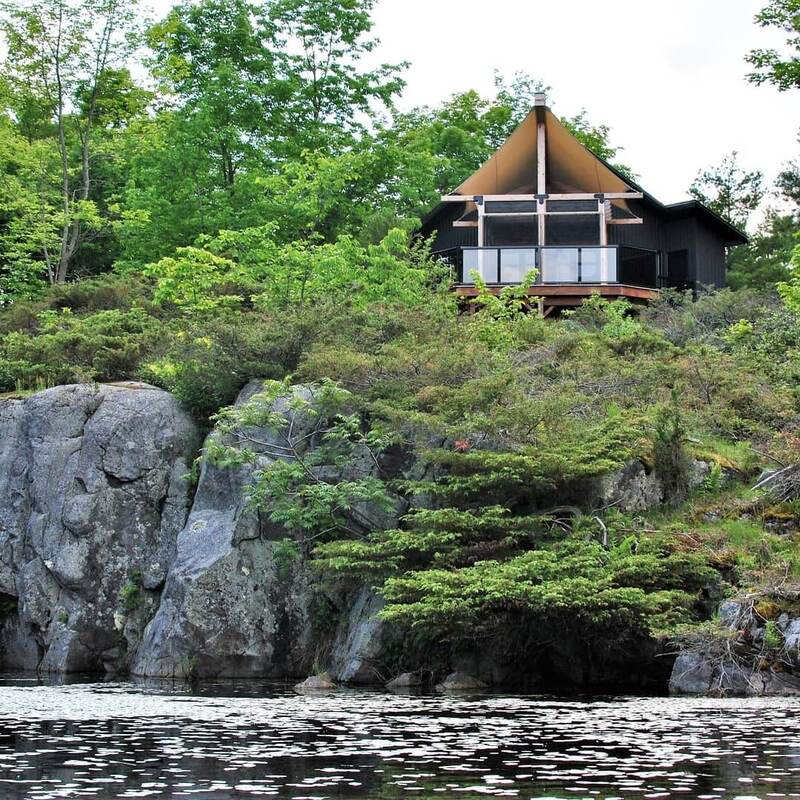 Modern glamping cabin perched on a granite cliff overlooking pond